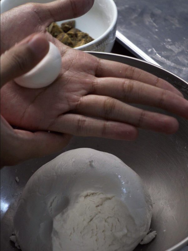 Pressing a small ball of dough flat in the palm