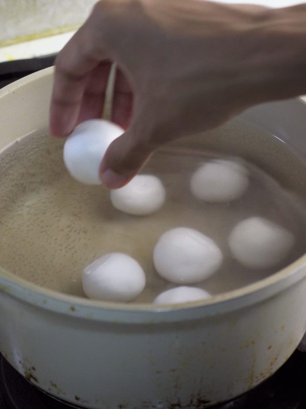 Dropping rice balls one by one into a pot of boiling water