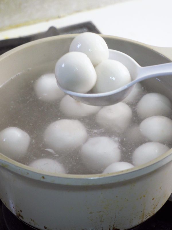 Cooked rice balls floating, lifted out of the pot with a ladle