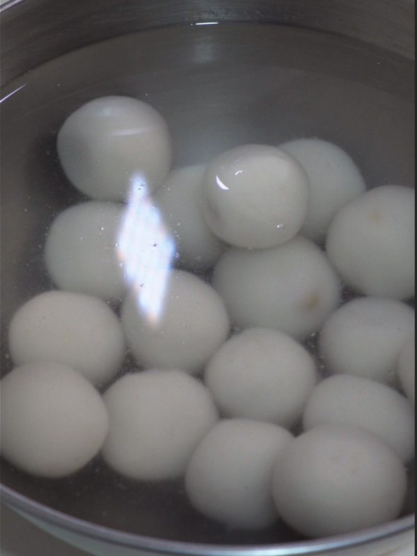 Cooked rice balls cooling in a bowl of ice water